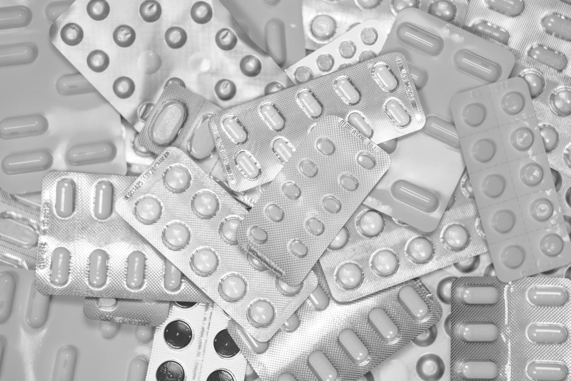 Monochrome close-up of assorted blister packs with pills, highlighting pharmaceutical packaging.