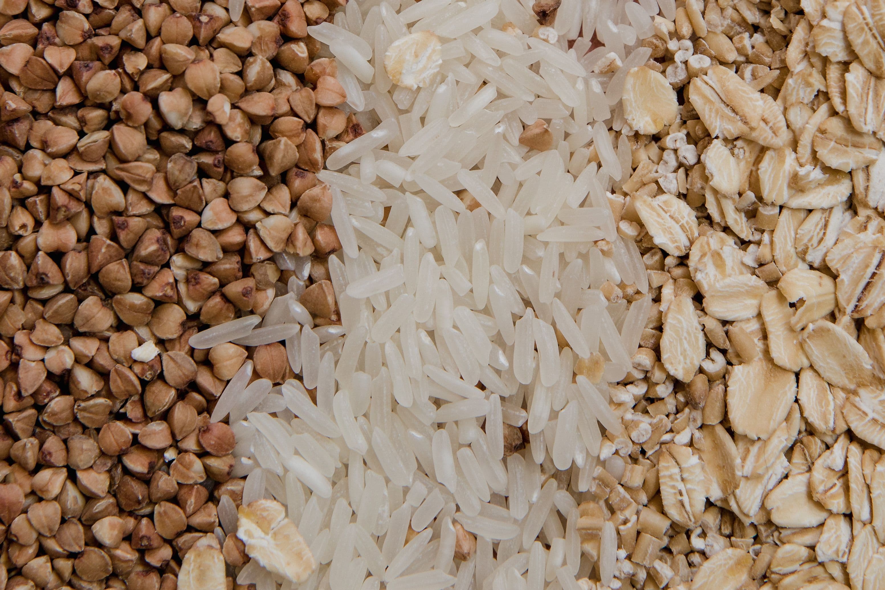 Close-up of assorted raw grains including buckwheat, rice, and oats, highlighting healthy food choices.