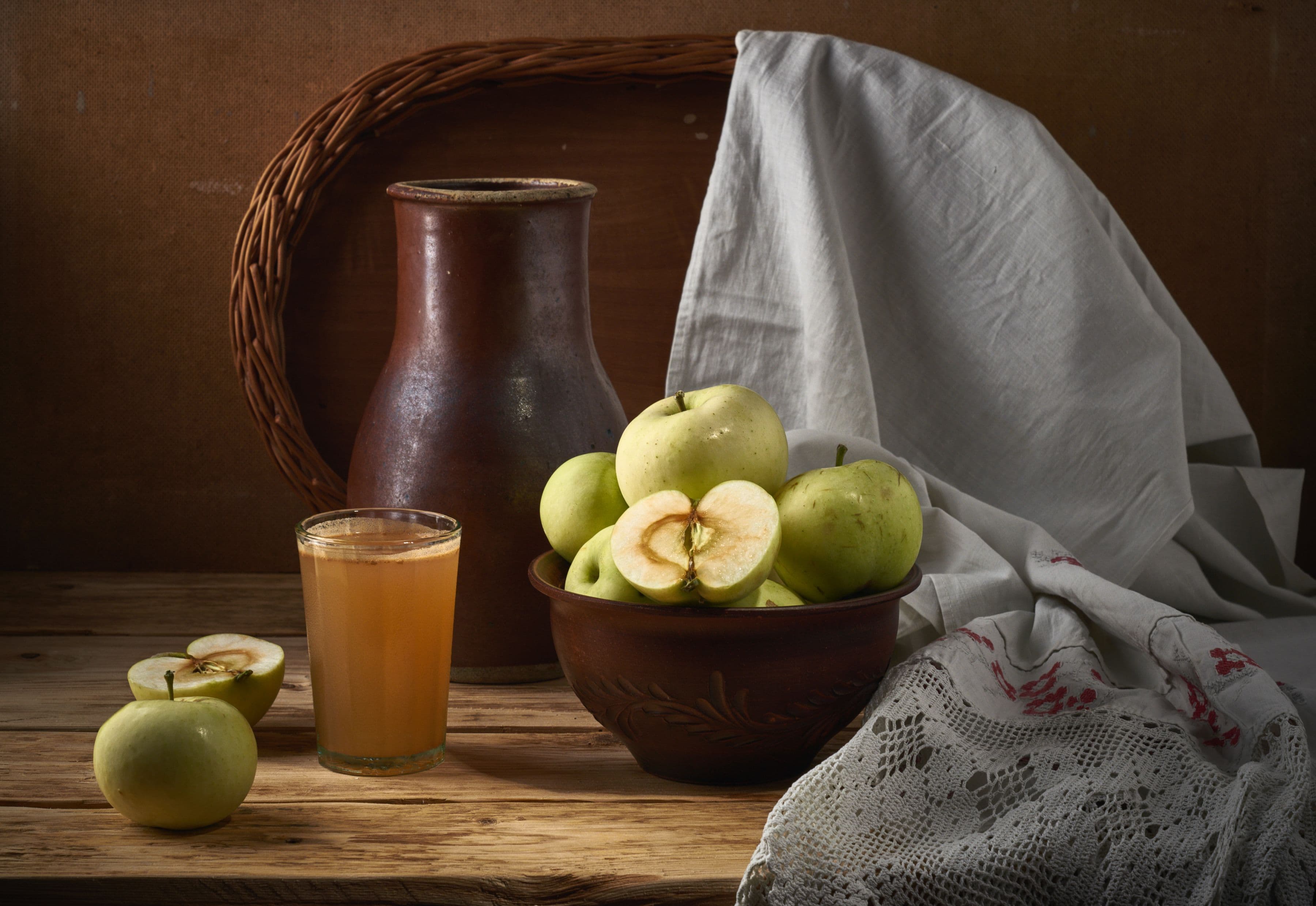 A rustic arrangement of apples, juice, and earthenware, evoking a cozy kitchen vibe.